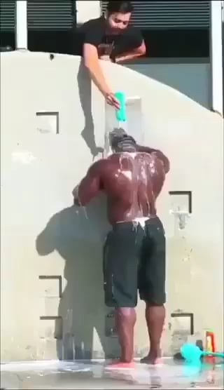Man taking a shower, another man pours water on him