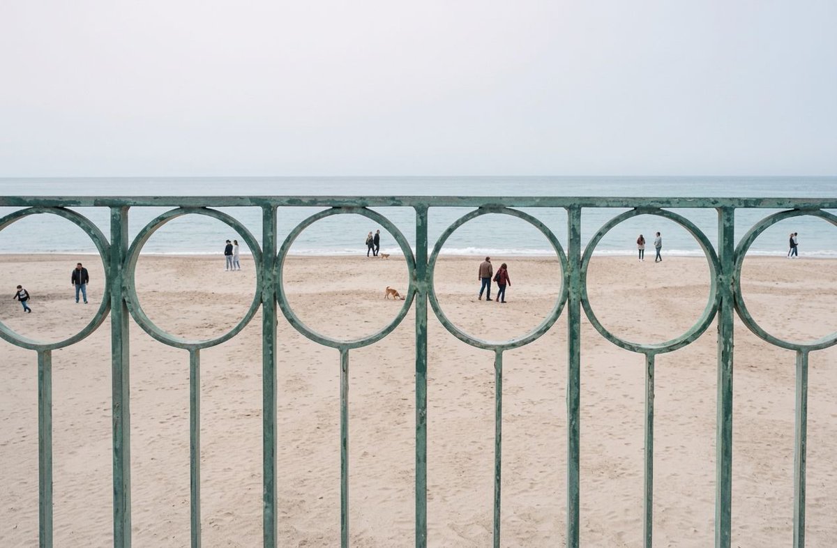 People on the beach seen through a circular fence